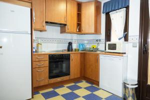 a kitchen with wooden cabinets and white appliances at Asturica in Astorga