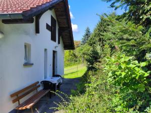 a wooden bench next to a white building at Am Springelbach in Hinternah