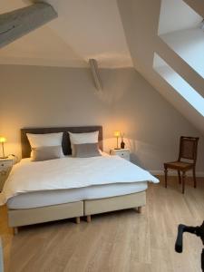 a bedroom with a large white bed and a chair at Gestorfer Kötnerhof Business und Landlust in Springe