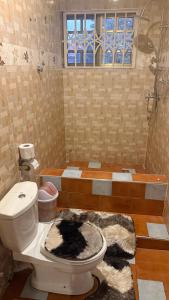 a bathroom with a toilet with a rug on the floor at LOUNEL BnB in Kumasi +6 photos