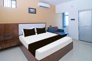 Un dormitorio con una cama grande y una silla. en Hotel O MG International, en Jamshedpur 21 fotos más