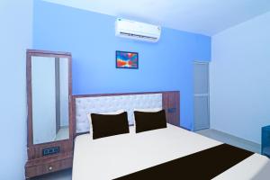 Dormitorio azul con cama y espejo en Hotel O MG International, en Jamshedpur