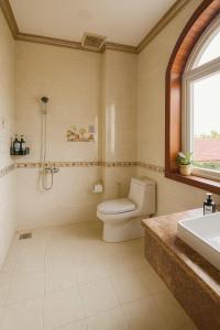 ein Badezimmer mit Toilette und Waschbecken und einem Fenster in der Unterkunft Luxurious River Castle 7 bedrooms in Ho-Chi-Minh-Stadt