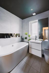 a white bathroom with a large tub and a sink at JW Executive ApartHouse 2 in Glasgow