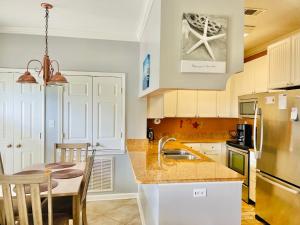 a kitchen with white cabinets and a table and a sink at 146 Beau Clair - Beachside Townhome with Pool in Long Beach in Long Beach