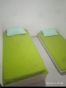 two beds in a room with green sheets and pillows at Paraíso de porto in Porto De Galinhas