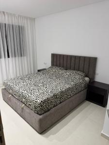 a bedroom with a bed with a black and white comforter at Residence Rmilat Garden Martil in Martil