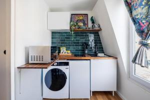 a small kitchen with a washer and dryer at Studio Exotique Hyper-Centre Enghien 12min Paris in Enghien-les-Bains