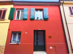 un edificio rosso con due finestre e una porta di Casa delle zie Savoretti a San Clemente