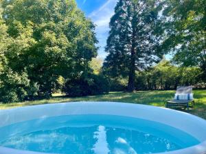 ein Whirlpool in einem Hof mit einem Stuhl und Bäumen in der Unterkunft Gîte Du Petit Manoir De La Noue in Cornillé
