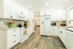 a white kitchen with white appliances and wooden floors at Oleander Drive - Coquina Sands in Naples