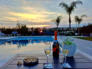 a bottle of wine and two glasses on a table by a pool at Hotel Ohana in Rome