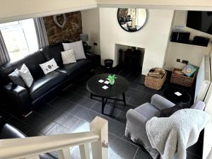 a living room with a black leather couch and a table at Ivy Cottage in Swansea