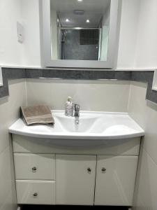 a bathroom with a white sink and a mirror at Ivy Cottage in Swansea