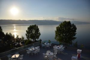 a patio with tables and chairs and a view of the water at Hotel Pogradeci 2 in Pogradec