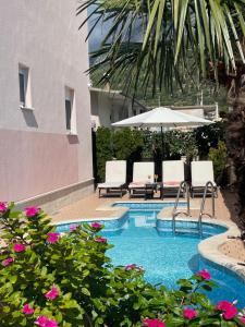 a swimming pool with two chairs and an umbrella at Apartmani Podest II in Baška Voda