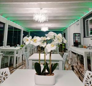 a dining room with white tables and white flowers at Hotel Ohana in Rome