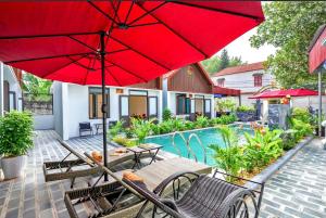 a patio with a table and chairs and a red umbrella at Tam Coc Anna Villa in Ninh Binh