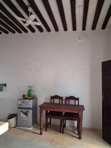 a table and two chairs in a room with a ceiling at Amani Guest House Lamu in Lamu