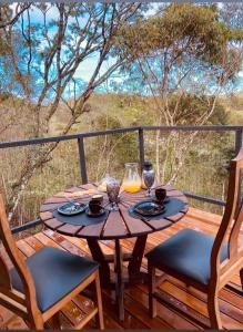 a wooden table on a deck with two chairs at Cabana Fé Miguel Pereira Com Ofuro e Por do Sol in Miguel Pereira