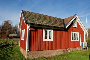 a red house with a chair in front of it at Sommargyllen Torp Brändabo in Torsås