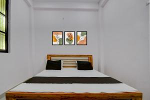 a bed in a white room with three pictures on the wall at HOTEL O AS PALACe in Lucknow