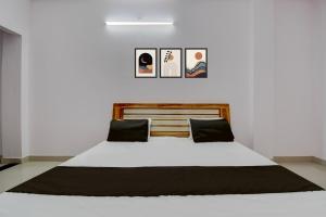 a bedroom with a white bed with three pictures on the wall at HOTEL O AS PALACe in Lucknow