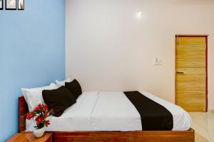 1 dormitorio con 1 cama blanca y un jarrón de flores en Hotel O R R Comforts Boarding and Lodging, en Nelamangala