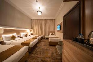 a hotel room with four beds and a television at Afaq Taiba Hotel in Medina +52 photos
