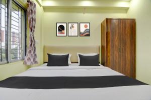 a bedroom with a bed and a wooden cabinet at Hotel O Jerry Guest House & Caf� By CheckIn in Bishnupur