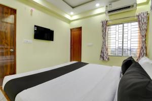 a bedroom with a bed and a tv and a window at Hotel O Jerry Guest House & Caf� By CheckIn in Bishnupur