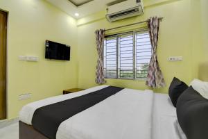 a bedroom with a large bed and a window at Hotel O Jerry Guest House & Caf� By CheckIn in Bishnupur