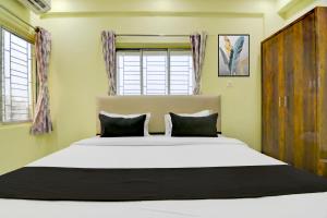 a bedroom with a large white bed with black pillows at Hotel O Jerry Guest House & Caf� By CheckIn in Bishnupur +25 photos