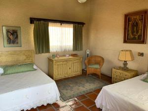 a bedroom with two beds and a chair and a window at Un oasis de tranquilidad y diversión familiar in Yautepec