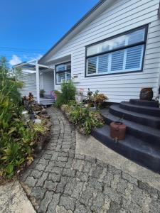 a home with a stone walkway in front of a house at Unique city bungalow in Whangarei