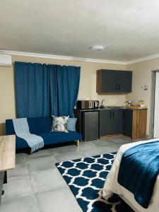 a living room with a blue couch and a kitchen at Hope Villa Luxury Accomodation in Odendaalsrus