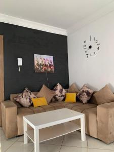 un salon avec un canapé et une horloge au mur dans l'établissement Résidence MaRwa, à Oulad Kerroum