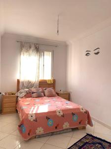 une chambre avec un lit avec une couette orange dans l'établissement Résidence MaRwa, à Oulad Kerroum