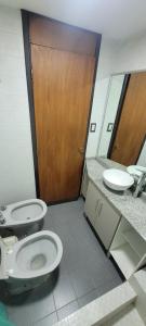 La salle de bains est pourvue de 2 toilettes et d'une porte en bois. dans l'établissement Departamento Plaza San Martín, à Córdoba