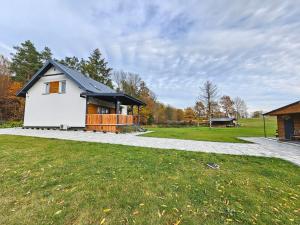 a white house with a black roof on a grass field at Ostoja SOWIBÓR in Dołgie