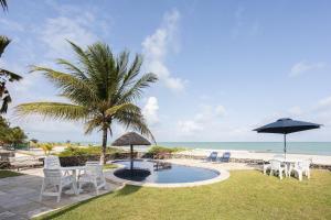 a pool with chairs and an umbrella and the beach at Cohost Casa Pedra do Anel in Vila Velha