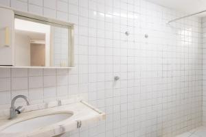 a white tiled bathroom with a sink and a mirror at Cohost Casa Pedra do Anel in Vila Velha +41 photos