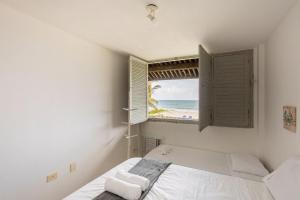 a bedroom with a bed and a window with the beach at Cohost Casa Pedra do Anel in Vila Velha