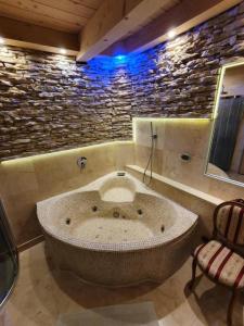 a large tub in a bathroom with a stone wall at Domki góralskie z sauną i jacuzzi in Kościelisko +21 photos