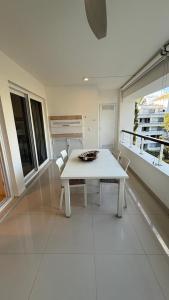 ein weißer Tisch und Stühle in einem Raum mit Fenstern in der Unterkunft Green Park hermoso apartamento vista al lago in Punta del Este + 71 Fotos