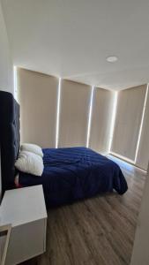 ein Schlafzimmer mit einem Bett mit einer blauen Decke in der Unterkunft Departamento en Angelópolis in El Gallinero