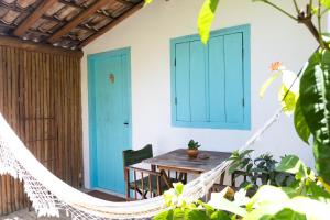 a hammock on the porch of a house with a table at Pousada do Rio Caraíva in Caraíva