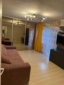 een woonkamer met een bruine bank en een woonkamer met gordijnen bij Apartament Str Crinului Cluj in Cluj-Napoca