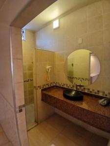 a bathroom with a sink and a mirror and a shower at Motel Encontros in Poá