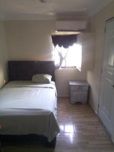 a bedroom with a white bed and a window at La Casa de Manccini in Santo Domingo